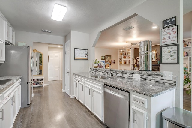 6325 Wallingford Dr, Fort Worth, TX 76133 - kitchen featuring appliances with stainless steel finishes, a sink, wood finished floors, white cabinetry, and backsplash