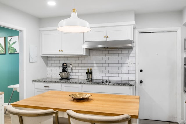 7017 Robinhood Ln, Fort Worth, TX 76112 - kitchen featuring under cabinet range hood, decorative backsplash, white cabinetry, and light stone counters
