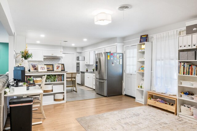 7017 Robinhood Ln, Fort Worth, TX 76112 - kitchen with stainless steel appliances, light wood finished floors, tasteful backsplash, white cabinets, and recessed lighting