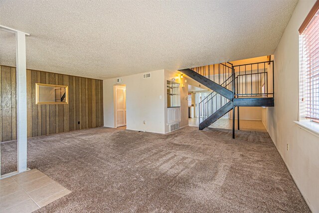 3626 Holly Tree Trl, Garland, TX 75044 - unfurnished living room featuring a textured ceiling, stairs, carpet flooring, and wooden walls