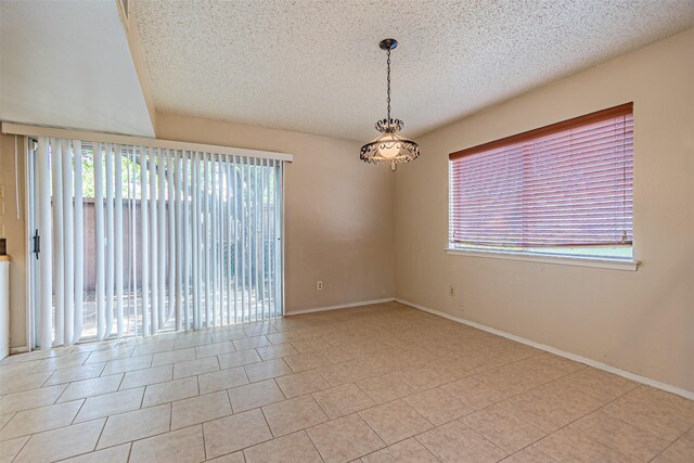 3626 Holly Tree Trl, Garland, TX 75044 - tiled empty room featuring plenty of natural light, a textured ceiling, and baseboards