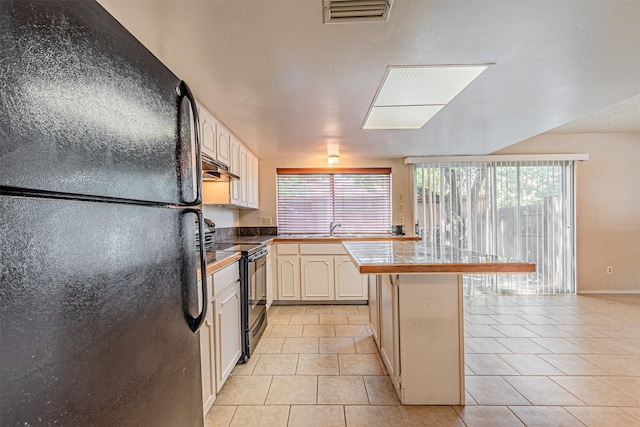 3626 Holly Tree Trl, Garland, TX 75044 - kitchen featuring black appliances, a sink, light tile patterned flooring, under cabinet range hood, and a peninsula
