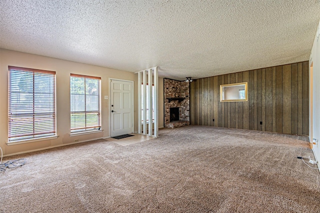 3626 Holly Tree Trl, Garland, TX 75044 - unfurnished living room with carpet floors, a textured ceiling, wood walls, and a brick fireplace