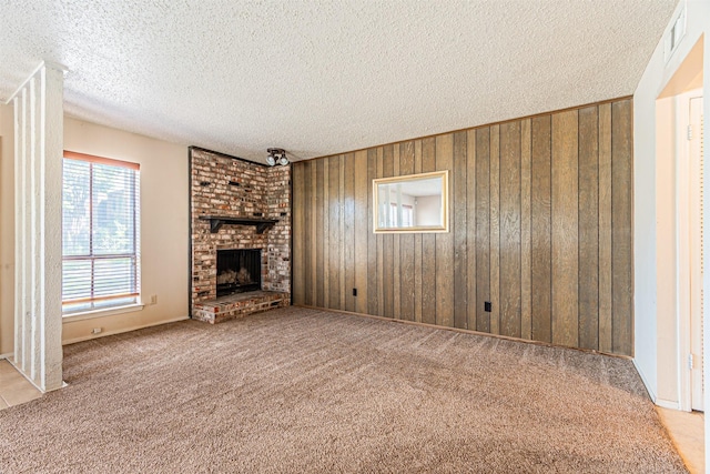 3626 Holly Tree Trl, Garland, TX 75044 - unfurnished living room featuring a textured ceiling, wood walls, carpet flooring, and a brick fireplace