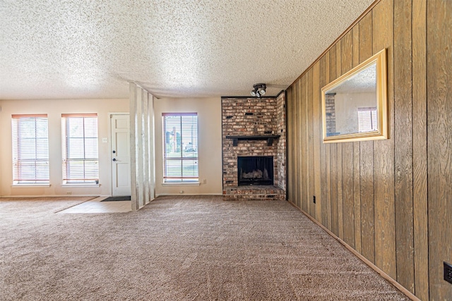 3626 Holly Tree Trl, Garland, TX 75044 - unfurnished living room featuring carpet flooring, a fireplace, wooden walls, and a textured ceiling