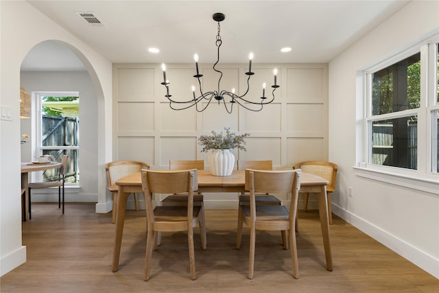 15616 Terrace Lawn Cir, Dallas, TX 75248 - dining space with a decorative wall, a chandelier, arched walkways, light wood-style flooring, and baseboards