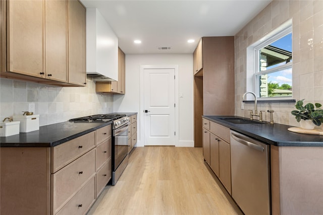 15616 Terrace Lawn Cir, Dallas, TX 75248 - kitchen featuring appliances with stainless steel finishes, a sink, light wood-style floors, dark countertops, and tasteful backsplash