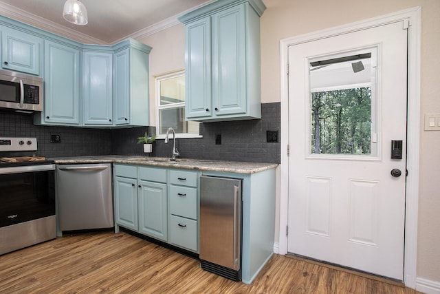 632 County Road 1952, Yantis, TX 75497 - kitchen featuring appliances with stainless steel finishes, blue cabinets, wood finished floors, a sink, and decorative backsplash