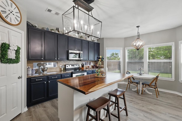 2304 Ranch House Dr, Denton, TX 76210 - kitchen featuring appliances with stainless steel finishes, wooden counters, a chandelier, light wood-style flooring, and tasteful backsplash