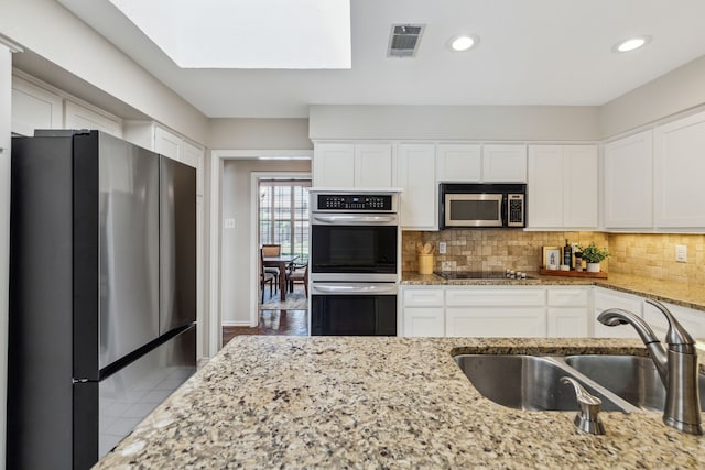 4406 Cobblers Ln, Dallas, TX 75287 - kitchen with appliances with stainless steel finishes, a sink, white cabinets, decorative backsplash, and recessed lighting