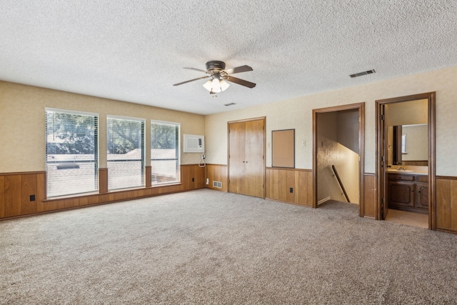 4406 Cobblers Ln, Dallas, TX 75287 - unfurnished bedroom with wainscoting, a textured ceiling, wood walls, carpet flooring, and an AC wall unit