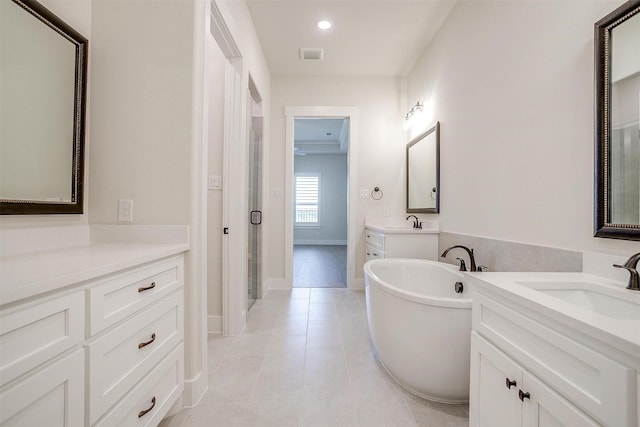 6145 Lucia Dr, Fort Worth, TX 76123 - bathroom featuring two vanities, a freestanding tub, tile patterned flooring, a stall shower, and recessed lighting