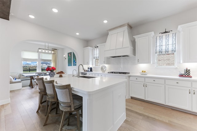 2880 Meadow Dell Dr, Prosper, TX 75078 - kitchen featuring a sink, premium range hood, arched walkways, light countertops, and white cabinetry