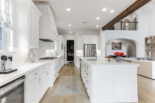 2880 Meadow Dell Dr, Prosper, TX 75078 - kitchen featuring wine cooler, a sink, appliances with stainless steel finishes, arched walkways, and white cabinetry