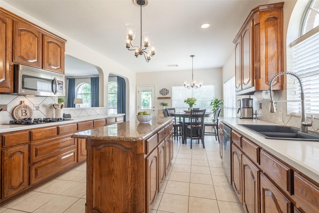 1312 Camberley Ct, Keller, TX 76248 - kitchen with stainless steel appliances, a sink, a chandelier, arched walkways, and backsplash