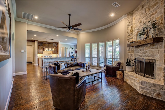 552 Horseshoe Bnd, Royse City, TX 75189 - living room featuring a ceiling fan, crown molding, a stone fireplace, dark wood-style floors, and arched walkways