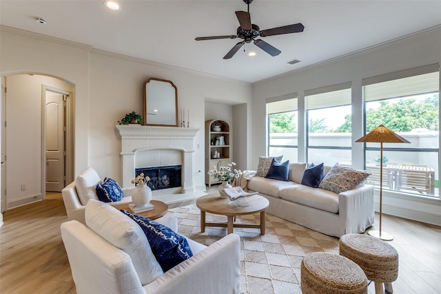 7904 Fair Oaks Ave, Dallas, TX 75231 - living area with crown molding, light wood-style flooring, a ceiling fan, arched walkways, and a fireplace with raised hearth