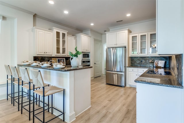 7904 Fair Oaks Ave, Dallas, TX 75231 - kitchen featuring appliances with stainless steel finishes, ornamental molding, a peninsula, backsplash, and a breakfast bar