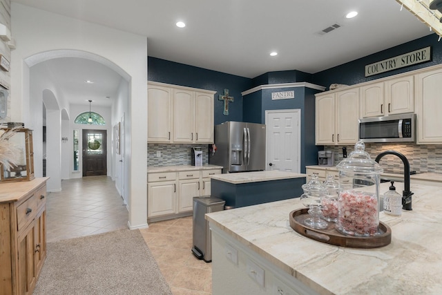 306 Hardeman Blvd, Justin, TX 76247 - kitchen with stainless steel appliances, arched walkways, backsplash, light countertops, and a kitchen island