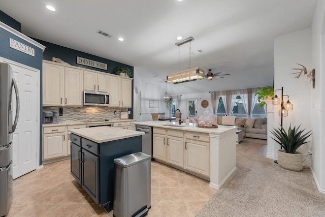 306 Hardeman Blvd, Justin, TX 76247 - kitchen featuring an island with sink, stainless steel appliances, a sink, cream cabinetry, and ceiling fan