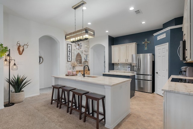 306 Hardeman Blvd, Justin, TX 76247 - kitchen featuring arched walkways, appliances with stainless steel finishes, a sink, a kitchen island with sink, and a kitchen breakfast bar