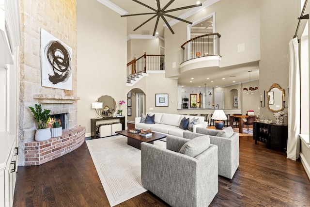 406 Wyndemere Blvd, Heath, TX 75032 - living area featuring arched walkways, ornamental molding, a brick fireplace, a towering ceiling, and dark wood-type flooring