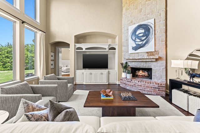 406 Wyndemere Blvd, Heath, TX 75032 - living room featuring built in features, a fireplace, dark wood-style flooring, a high ceiling, and arched walkways