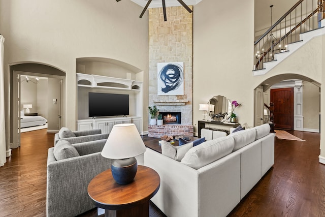 406 Wyndemere Blvd, Heath, TX 75032 - living room featuring a towering ceiling, arched walkways, stairs, dark wood finished floors, and a fireplace