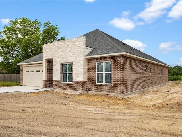 2799 Fm-3218, Commerce, TX 75428 - view of home's exterior with driveway, an attached garage, brick siding, and a shingled roof
