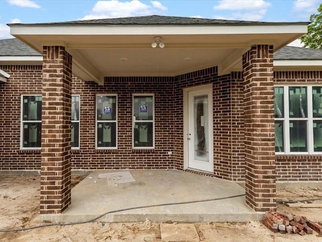 2799 Fm-3218, Commerce, TX 75428 - view of exterior entry with brick siding, a patio, and a shingled roof