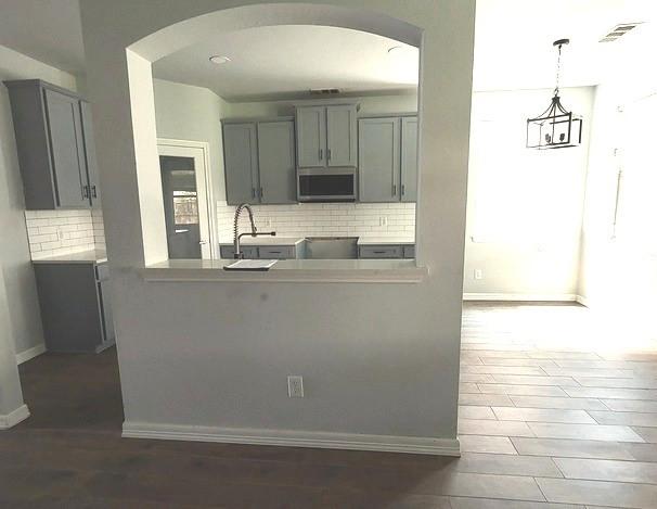 1207 Goldeneye, Aubrey, TX 76227 - kitchen featuring stainless steel microwave, gray cabinets, arched walkways, and a sink