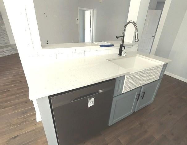 1207 Goldeneye, Aubrey, TX 76227 - kitchen featuring stainless steel dishwasher, dark wood-style flooring, a sink, light countertops, and baseboards