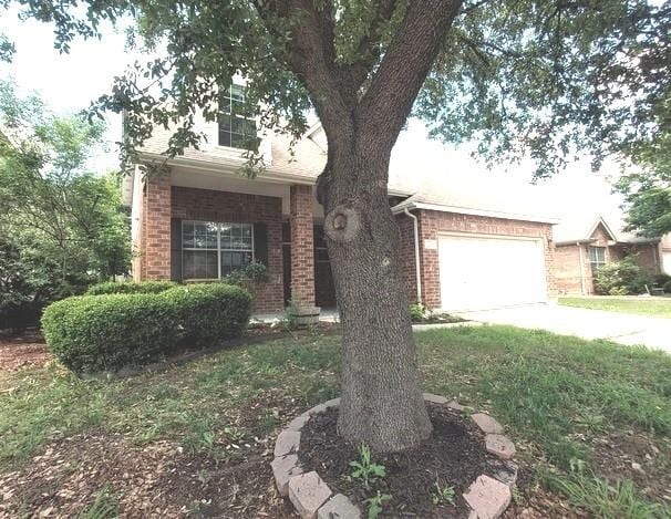 1207 Goldeneye, Aubrey, TX 76227 - view of property hidden behind natural elements featuring brick siding, concrete driveway, and a garage