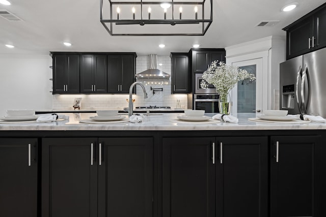 5316 Humbert Ave, Fort Worth, TX 76107 - kitchen with wall chimney exhaust hood, appliances with stainless steel finishes, dark cabinetry, backsplash, and ornamental molding