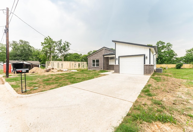128 Goodman St, Sulphur Springs, TX 75482 - view of front of home featuring an attached garage, concrete driveway, cooling unit, brick siding, and a front lawn
