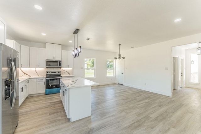 128 Goodman St, Sulphur Springs, TX 75482 - kitchen with appliances with stainless steel finishes, a chandelier, a kitchen island, light stone counters, and white cabinets