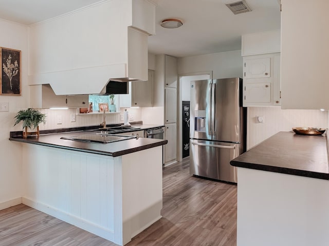 461 E Bradley St, Fairfield, TX 75840 - kitchen featuring stainless steel fridge with ice dispenser, dark countertops, a peninsula, light wood-style flooring, and a sink