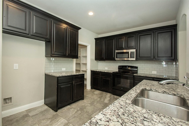3613 Pisa Mews, Dallas, TX 75236 - kitchen featuring stainless steel microwave, black range with electric stovetop, a sink, decorative backsplash, and light stone countertops