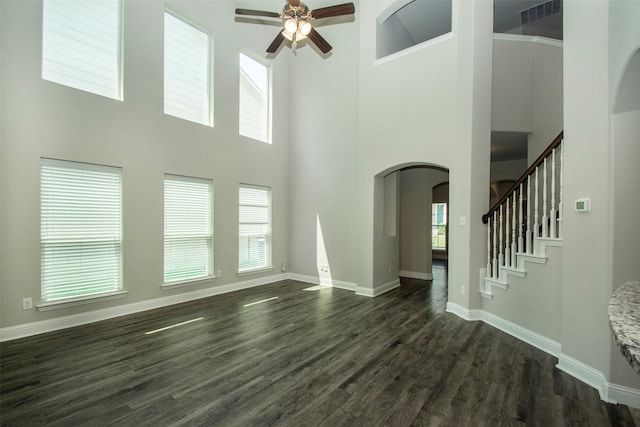 3613 Pisa Mews, Dallas, TX 75236 - unfurnished living room featuring arched walkways, a ceiling fan, a towering ceiling, dark wood-style floors, and baseboards
