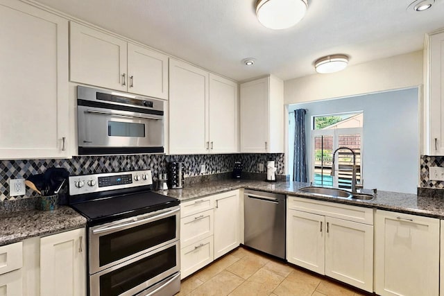 7109 Alpha Rd, Dallas, TX 75240 - kitchen featuring stainless steel appliances, a sink, backsplash, white cabinets, and light tile patterned flooring