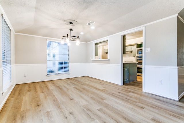 2 Linderhof Cir, Bedford, TX 76022 - unfurnished dining area with a chandelier, wainscoting, a textured ceiling, light wood-style flooring, and crown molding