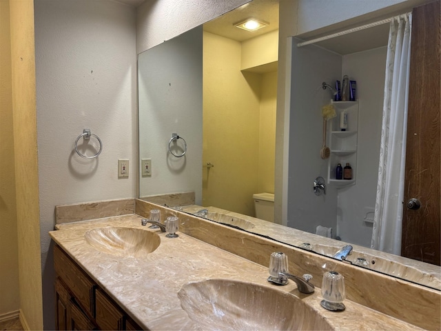 2317 Cliffside Dr, Plano, TX 75023 - bathroom featuring double vanity, a textured wall, and toilet