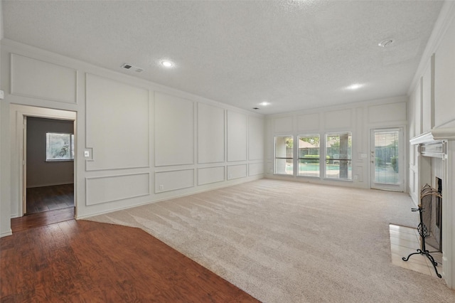 1521 Treeline Dr, Desoto, TX 75115 - unfurnished living room with a decorative wall, a textured ceiling, a fireplace with flush hearth, crown molding, and recessed lighting