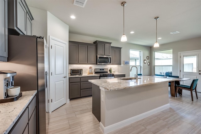 1824 Rachel St, Northlake, TX 76247 - kitchen featuring a sink, appliances with stainless steel finishes, light stone counters, an island with sink, and backsplash