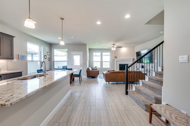 1824 Rachel St, Northlake, TX 76247 - kitchen with a sink, a glass covered fireplace, light stone countertops, hanging light fixtures, and ceiling fan