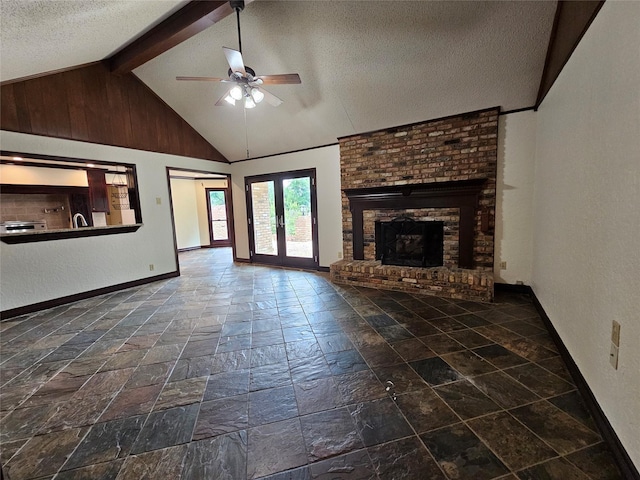 236 La Jolla Dr, Athens, TX 75751 - unfurnished living room featuring stone tile flooring, a textured ceiling, baseboards, a ceiling fan, and a fireplace