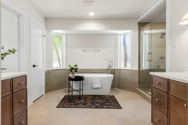 2626 Club Meadow Dr, Garland, TX 75043 - full bathroom with vanity, a stall shower, a freestanding bath, wainscoting, and tile walls