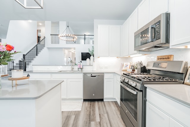 2049 Hartley Dr, Forney, TX 75126 - kitchen featuring appliances with stainless steel finishes, a sink, a chandelier, light wood-style floors, and light countertops