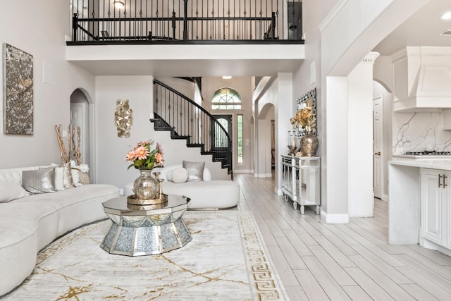 14237 Sugar Hill Dr, Little Elm, TX 75068 - living room with arched walkways, a towering ceiling, stairs, light wood-type flooring, and baseboards
