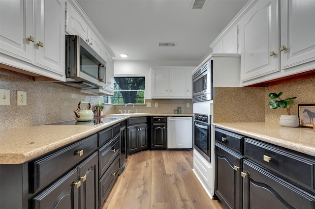 4909 Berkeley Ct, Garland, TX 75043 - kitchen featuring appliances with stainless steel finishes, white cabinets, light wood finished floors, a sink, and recessed lighting